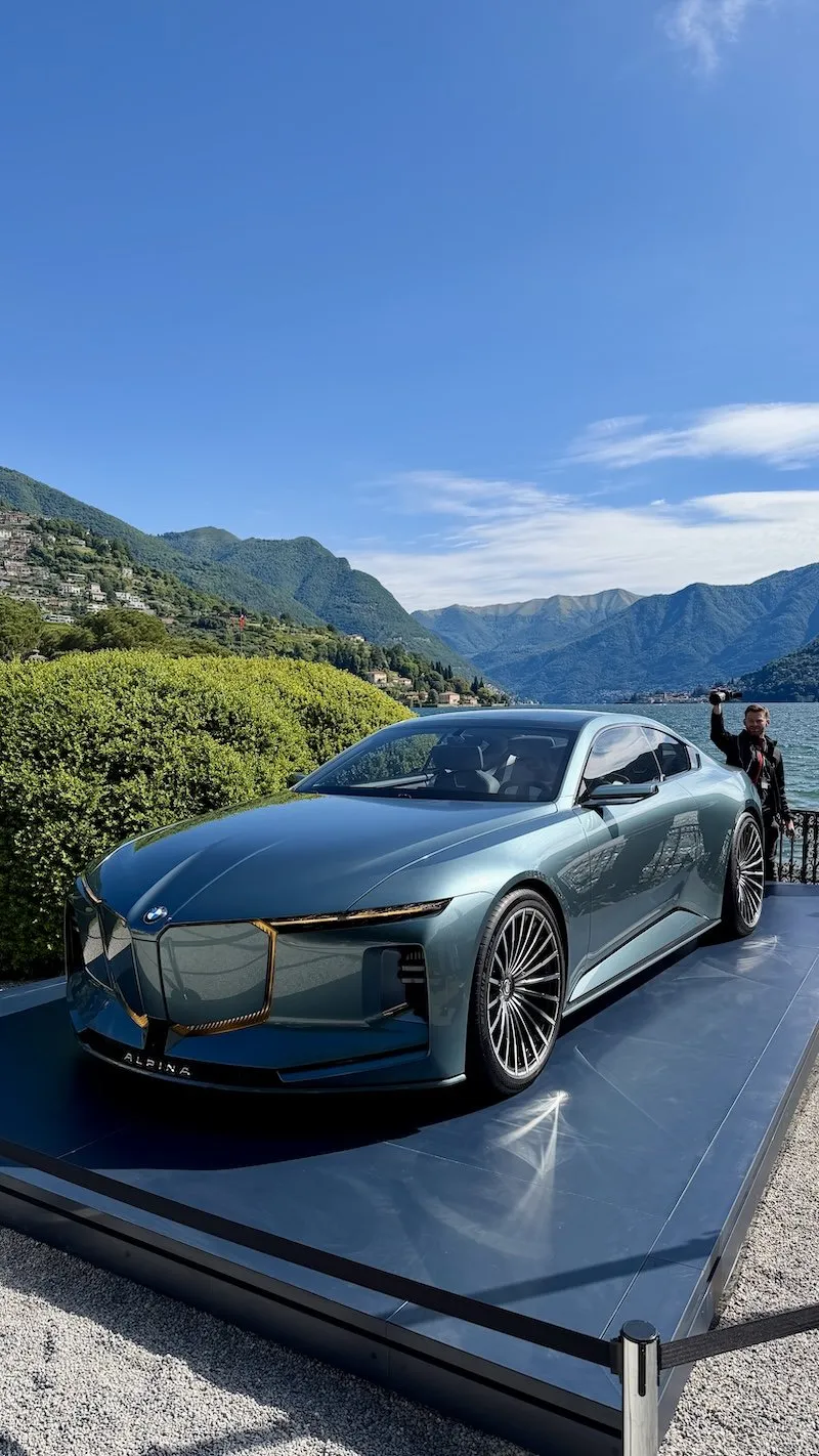 The Vision BMW Alpina concept coupé on its display platform at the Concorso d’Eleganza, with Lake Como and the mountains behind it.