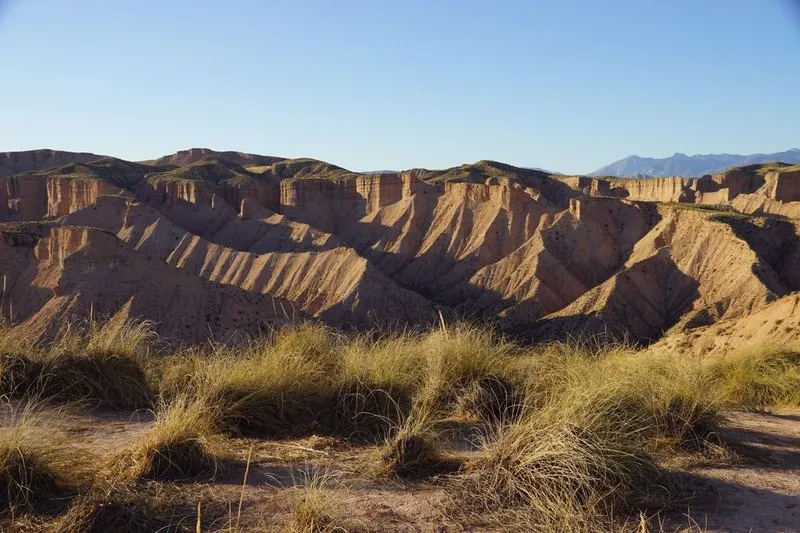 Eroded badlands slopes with dry grass in Andalusia, mountains far off on the horizon.