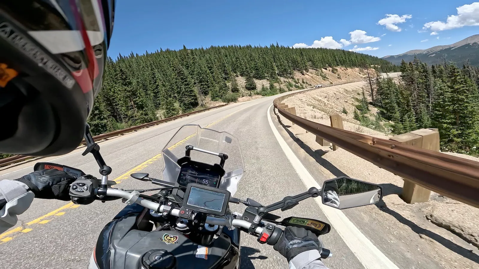 Rider's-eye view from the Aprilia Tuareg 660 cockpit on a paved Colorado mountain pass with the Garmin on the bars