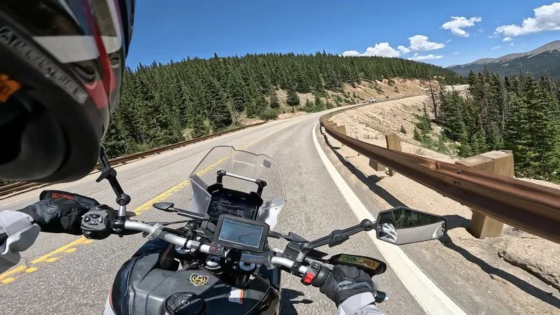 Rider’s-eye view from the Aprilia Tuareg 660 cockpit on a paved Colorado mountain pass, Garmin on the bars