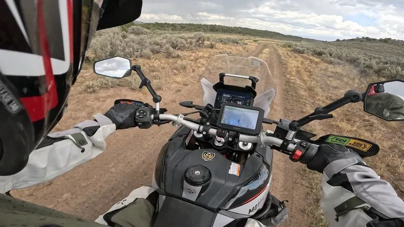 POV from the Aprilia Tuareg 660 bars on a sandy two-track through Colorado high-desert sagebrush