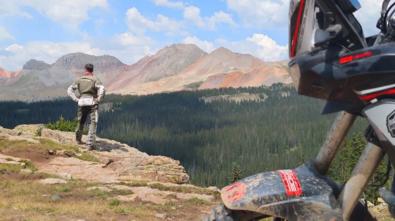 NastyNils standing beside the Aprilia Tuareg 660 on a ridge high above the San Juan mountains