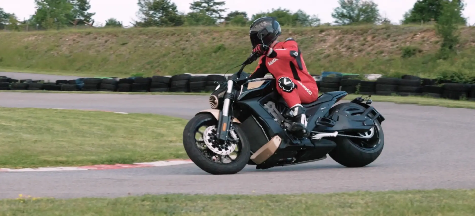 NastyNils rides the Benda LFC 700 PRO through a corner at the Bad Fischau supermoto circuit in Austria, wearing red Vanucci leathers and a black helmet. No other motorcycle is visible.