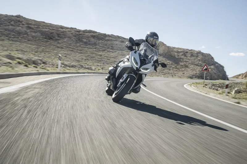 Nils on a BMW R 1250 RT, leaning hard through a Croatian coastal mountain road — full active tension, weight on the pegs, spine lengthened.