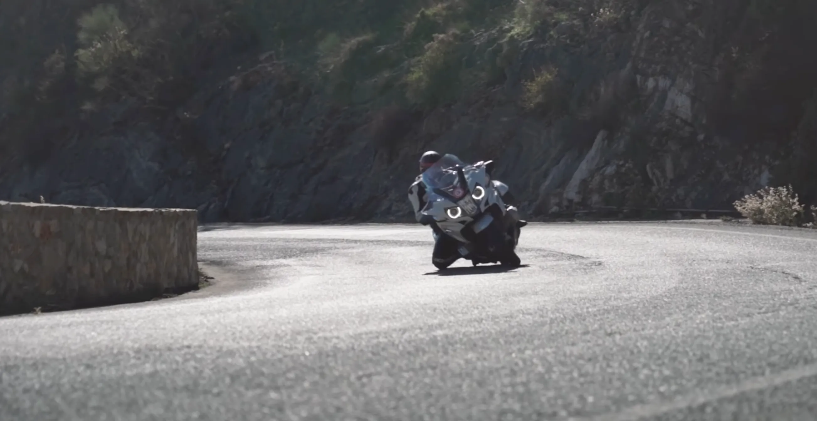 Nils on a BMW R 1250 RT in a tight mountain hairpin, knee close to the asphalt — full lean angle held by maintenance throttle and a controlled chassis state.
