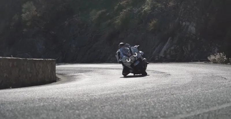 Nils on a BMW R 1250 RT in a tight mountain hairpin, knee close to the asphalt — full lean angle held by maintenance throttle and a controlled chassis state.
