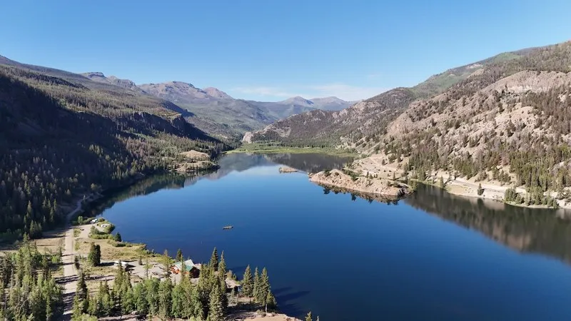 Aerial view of Lake San Cristobal in Colorado with forested ridges and a handful of cabins on the shore