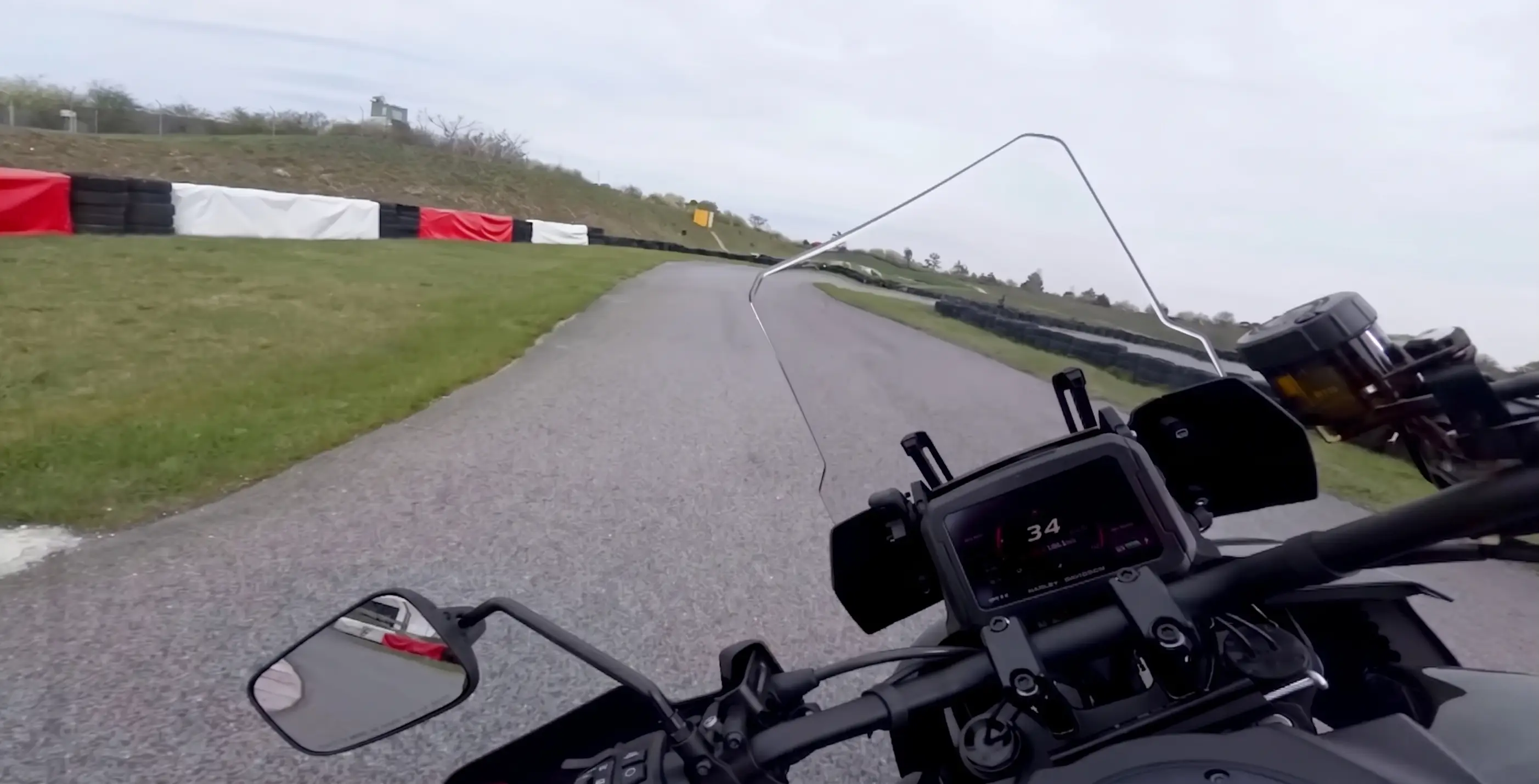Onboard view from a Harley-Davidson Pan America 1250 Limited 2026 on a closed supermoto track in Austria with overcast skies and dry asphalt.