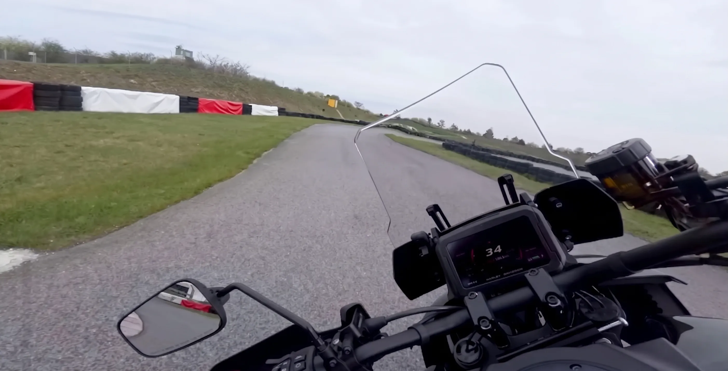 Onboard view from a Harley-Davidson Pan America 1250 Limited 2026 on a closed supermoto track in Austria with overcast skies and dry asphalt.