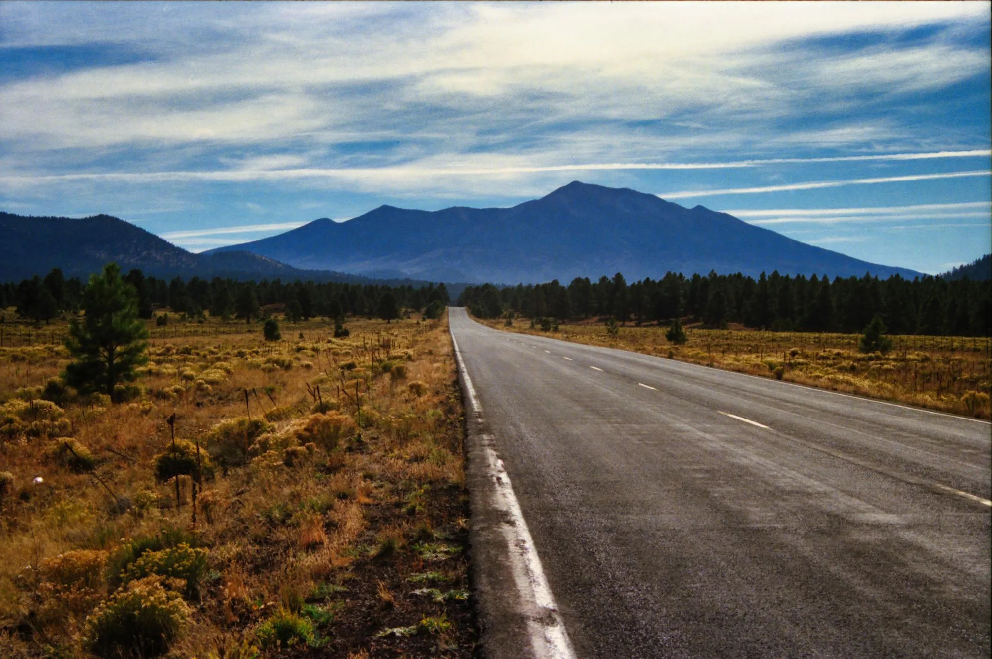 An open Arizona highway leading toward Mount Lemmon — the kind of long, unbroken touring road where passive slumping turns into back pain by hour three.