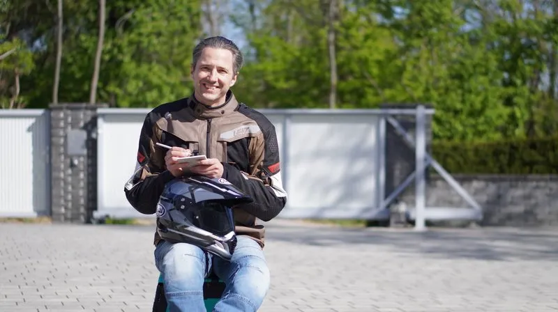 Nils Mueller in adventure-touring gear holding a dark motorcycle helmet, standing outdoors at the supermoto-track facility before the first lap of 2026.