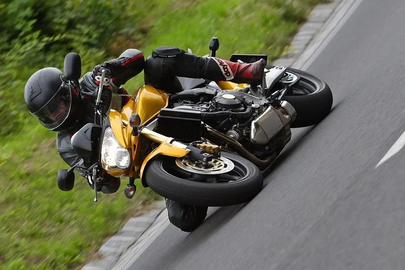 Nils cornering hard on a Honda CB600F Hornet through a left-hand bend on a rural country road — the lean angle that puts your torso into oncoming territory if your line is wrong.