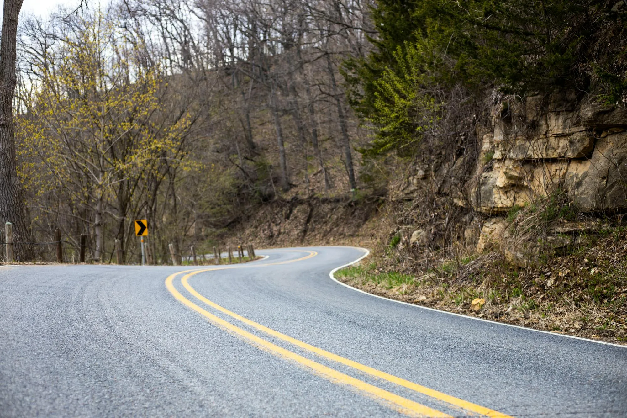 A wavy asphalt mountain road through Appalachian terrain — exactly the kind of blind left-hander where most riders drift wrong.