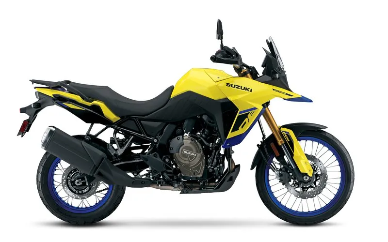 Suzuki V-Strom 800DE photographed side-on against a clean white studio backdrop, yellow-blue color scheme highlighting the adventure-sport fairing, spoked wheels, upright riding position, and dual-disc front brake setup.
