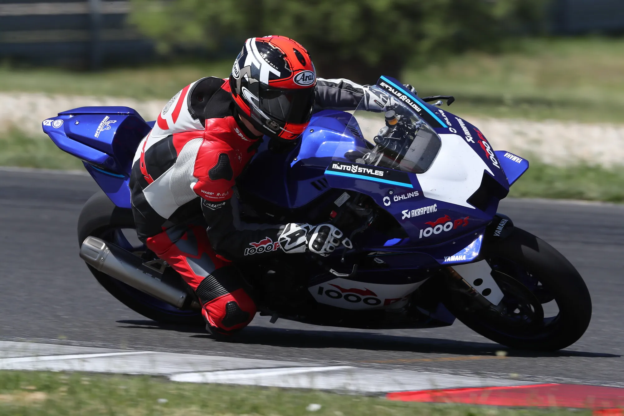 NastyNils deep in lean on a Yamaha YZF-R9 in full 1000PS race livery at Slovakia Ring. Akrapovic exhaust, Öhlins suspension, aggressive track pace. Action shot by professional photographer.